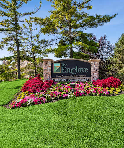 The entrance to The Enclave community with a sign and flowers.