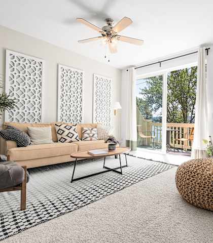 a living room with white walls and a sliding glass door leading to a balcony