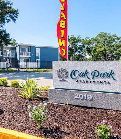A sign for Oak Park Apartments stands in front of a building.