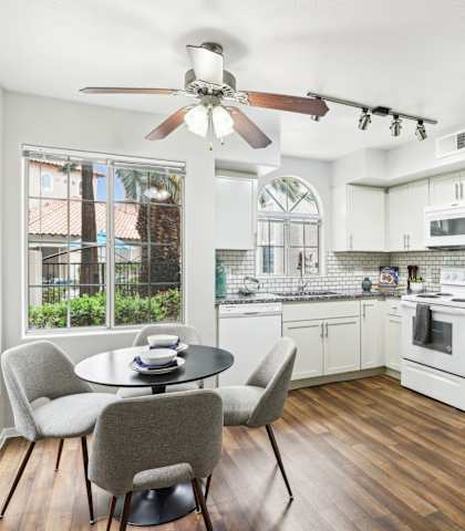 A kitchen with white appliances and a table with chairs.