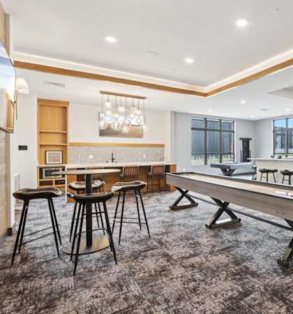 A room with a long table and chairs, a bar area, and a projection screen.