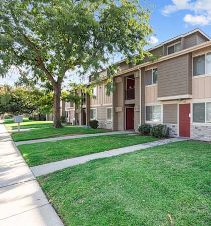 A row of townhouses with green lawns in front.