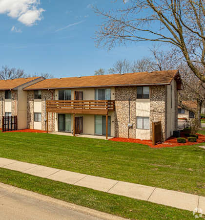 Apartment building with a sidewalk and green grass.