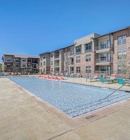 A large swimming pool in front of apartment buildings.