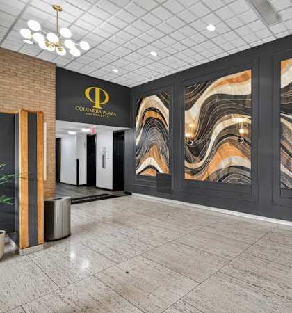 A hallway with a marble wallpaper design and a black and gold logo on the wall.
