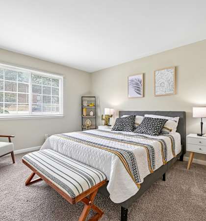 A bedroom with a bed, nightstand, and chair.