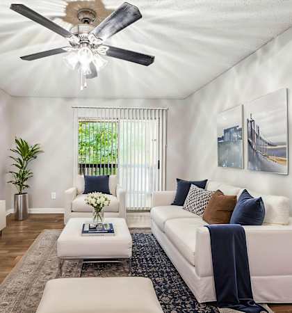 A living room with a white couch, a television, and a ceiling fan.