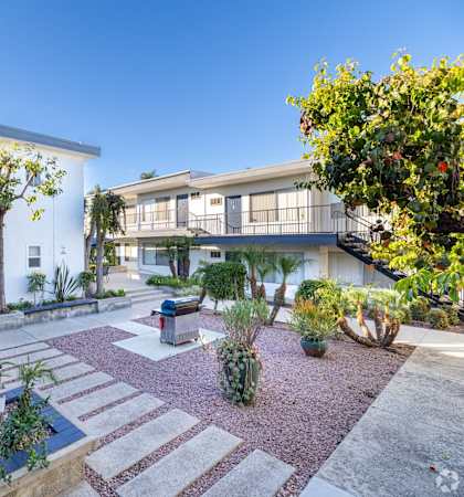 A courtyard with a small garden and a white building in the background.