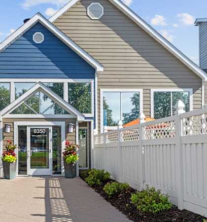 A blue and beige house with a white picket fence in front.