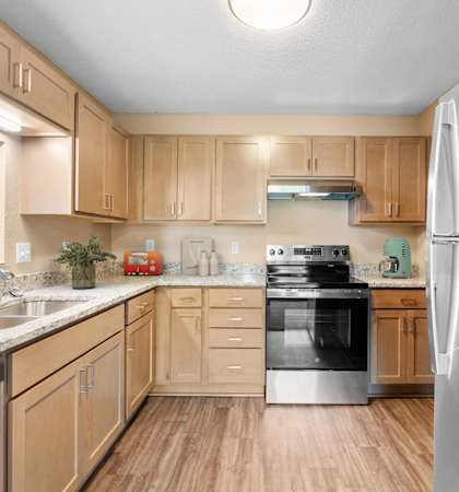 A kitchen with wooden cabinets and a stainless steel refrigerator.