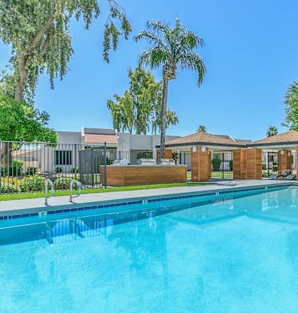 a swimming pool with trees and a building in the background at Tides on Southern, Arizona, 85204