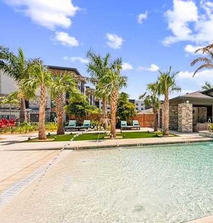 A swimming pool surrounded by palm trees and a house in the background.