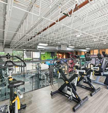 A gym with a variety of exercise equipment including treadmills, stationary bikes, and weight machines.