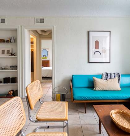 a living room with a blue couch and a table and chairs