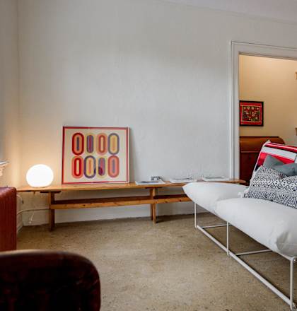 a living room with a white chair and a painting on the wall