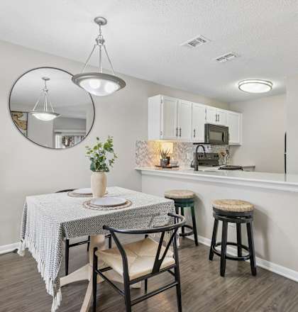 A dining area with a round mirror and a table with chairs.