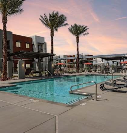 A swimming pool surrounded by palm trees and lounge chairs at Ironwood Ranch Apartments,Maricopa