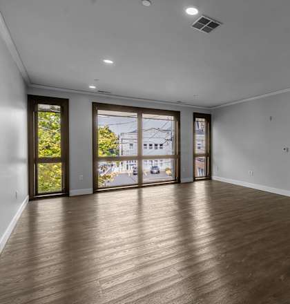 an empty living room with wood floors and a door to a balcony  at Nineteen North, Buffalo, 14202