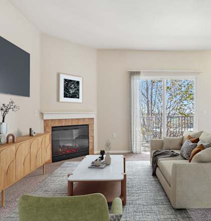 A living room with a fireplace, a couch, a chair, and a TV mounted on the wall.