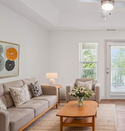 A living room with a grey couch, a wooden coffee table, a television, and a painting on the wall.