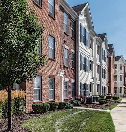 a brick apartment building with a tree in front of it at Brickshire Apartments, Merrillville