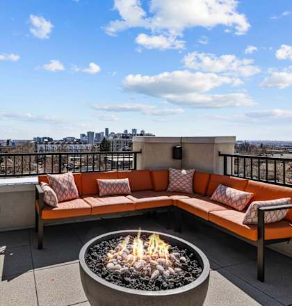 A patio with a fire pit and a view of the city.