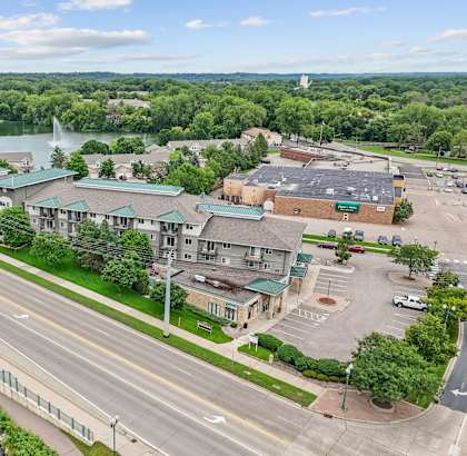 A road runs parallel to a body of water with a building on the right.
