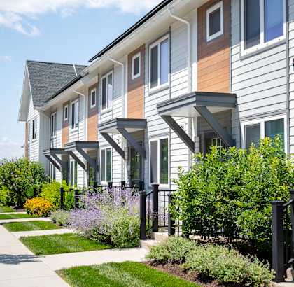 A row of townhouses with a sidewalk in front.