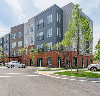a large apartment building with cars parked in a parking lot
