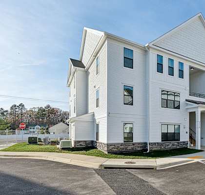 A white building with a parking lot in front.