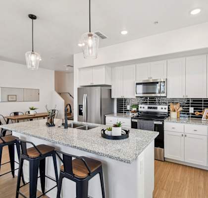A kitchen with a granite countertop and bar stools.
