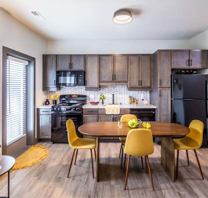 Studios in Butchertown KY - Martin on Main - Dine_in Kitchen with Brown Cabinets, Black Appliances, and Dining Room Table with Chairs.