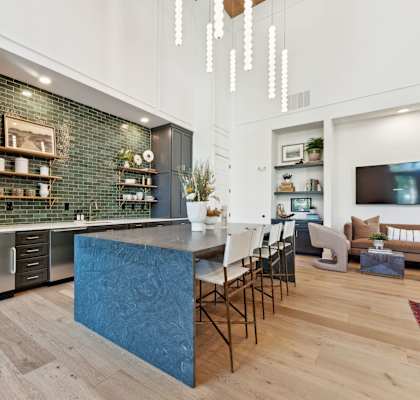 a kitchen with a blue island and a living room with a table and chairs