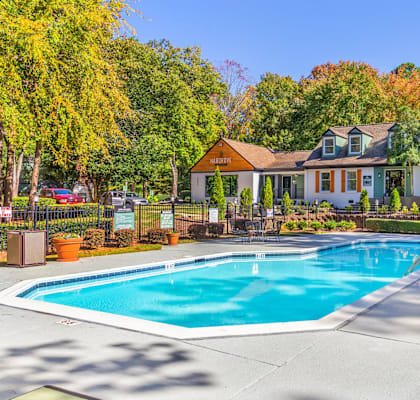 A large swimming pool in front of a house surrounded by trees.