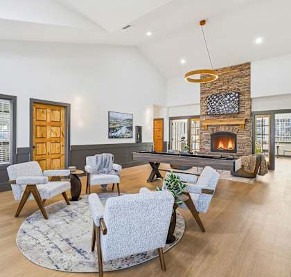 A living room with a stone fireplace and a large rug.