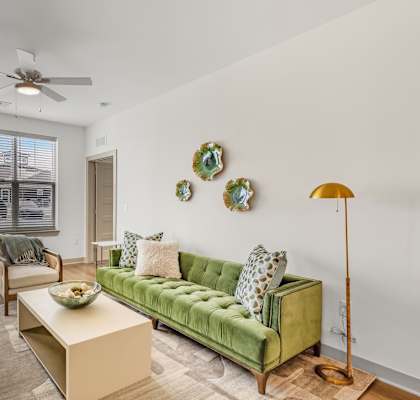 A living room with a green couch and a ceiling fan.