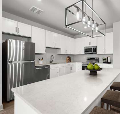 A modern kitchen with a white marble countertop and stainless steel appliances.