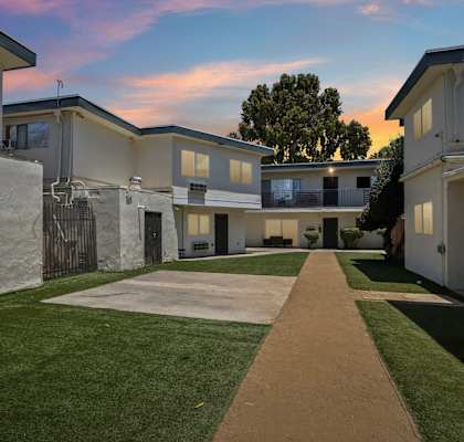 A pathway leads through a grassy area between two rows of houses.