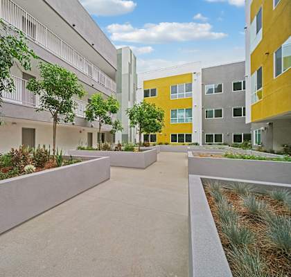 A courtyard with a concrete floor and a yellow building in the background.