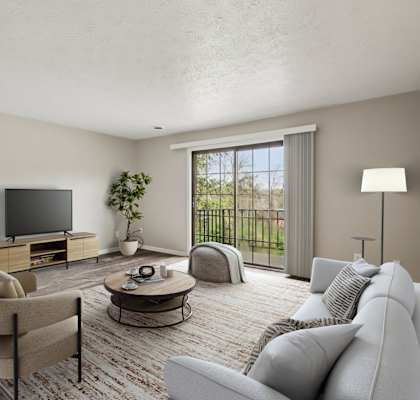 A living room with a grey couch, a chair, a coffee table, a television, and a potted plant.