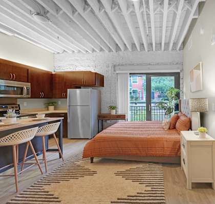 a bedroom with an orange bed and a kitchen