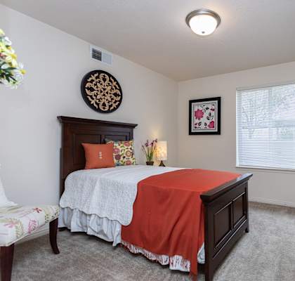 A bedroom with a bed, dresser, and window.