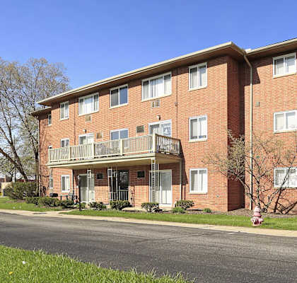 A red brick apartment building with a balcony on the second floor.