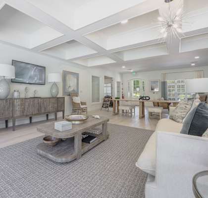 A spacious living room with a large grey rug and a white sofa.