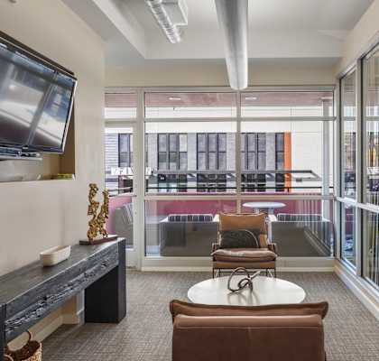 a living room with chairs and a television and a balcony