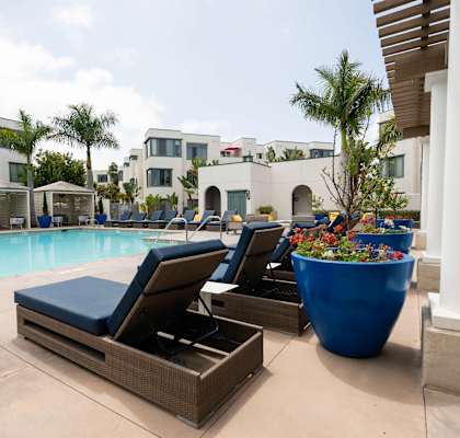 A poolside area with lounge chairs and a large planter.