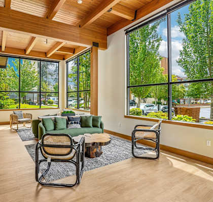 A living room with a couch, chairs, and a table with a view of the outdoors.
