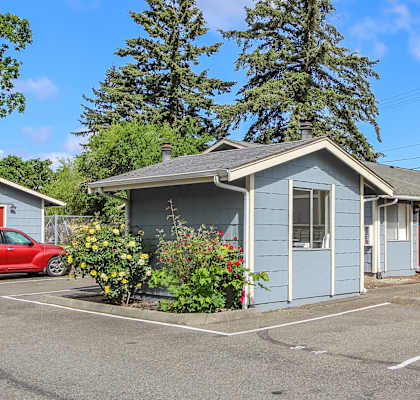 A small blue house with a red car parked in front.