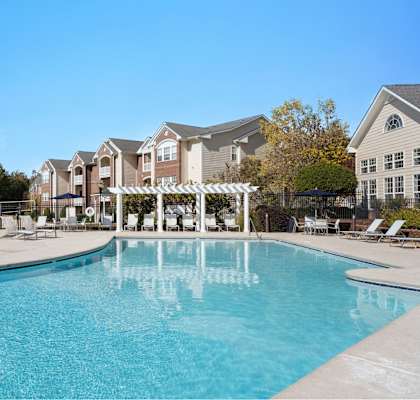 A large swimming pool in front of a building with a white pergola at Village on the Lake Apartments, North Carolina