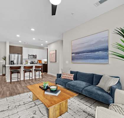 A living room with a blue couch and a painting on the wall.
